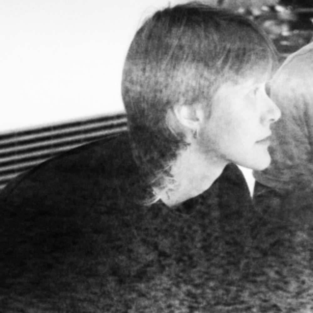 Black and white profile portrait of a young person with short hair wearing a dark top, looking to the right.