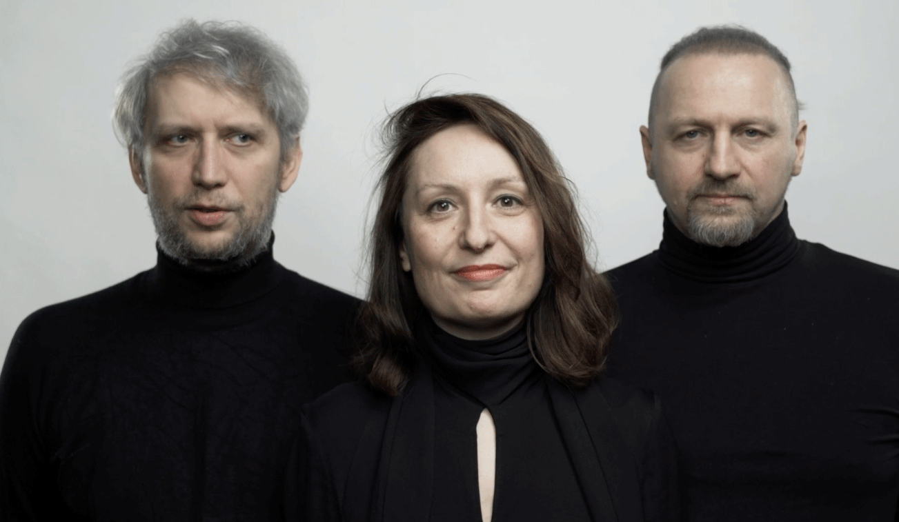 Portrait of two men and one woman wearing black turtlenecks against a plain light background.