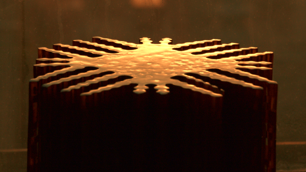Close-up of a star-shaped corrugated metal structure with golden reflective light on top.