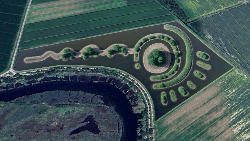 Aerial view of a landscaped water feature resembling a key shape surrounded by green agricultural fields.
